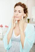 A brunette woman applying face cream