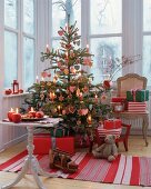 Classic Christmas tree decorated in red and white with gingerbread and fabric baubles and candles in conservatory
