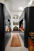 Modern, black cupboard installations with rounded edges in open-plan kitchen in traditional interior