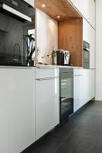 A white designer kitchen with a spruce wood niche and built in lights