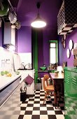 Purple walls, green metal locker and heating pipes in small kitchen with chequered floor