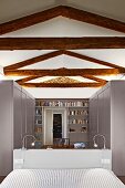 Renovated bedroom with exposed, rustic roof beam structure, bed with headboard, pale grey wardrobes and bookcase