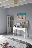 Wooden floor and walls painted in grey and pictures on console table in bedroom