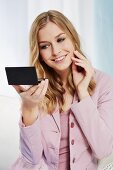 A blonde woman looking in a compact mirror