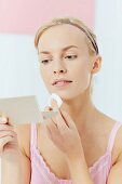 A young woman applying make-up with a sponge