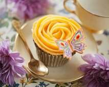 A butterfly cupcake with peach buttercream