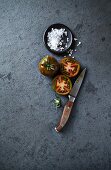 Stillleben mit schwarzen Tomaten, grobem Salz & Küchenmesser (Aufsicht)