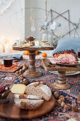 A picnic-style Christmas meal on a kilim rug with a cheese platter and roast ham