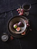 An arrangement of crockery with figs, grapes, spices and wine