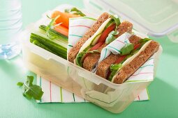 A cheese sandwich and raw vegetables in a lunch box