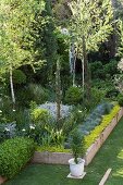 Stone-edged flowerbed and trees in garden