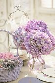 Bouquet of purple hydrangeas in glass vase next to basket of dried lavender