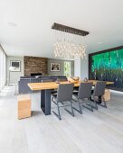 Grey cantilever chairs around wooden table with metal frame below pendant lamp with illuminated glass droplets in modern, open-plan interior