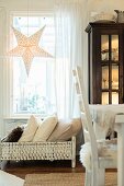 Illuminates paper star in window above cushions in old dolls' bed