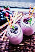 Berry smoothies in two screw-top jars with straws