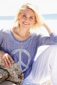 A blonde woman on a beach wearing a purple oil-washed T-shirt with a peace sign