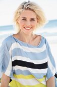 Blonde Frau in gestreiftem Oversize-Shirt am Strand
