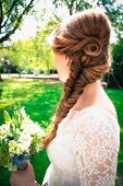 A bride with artistically plaited hair and a bouquet