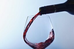 Rotwein wird in Glas eingeschenkt