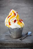 Frozen yoghurt in a metal cup with passion fruit purée and goji berries