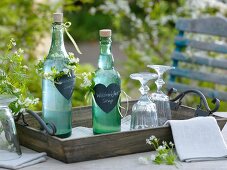 Bottles of homemade woodruff syrup as a gift decorated with hearts and wreaths