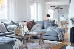 U-shaped grey sofa and rustic coffee table on trestles in open-plan living area