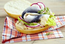 Herring on a burger bun with red onions