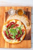 Pizza mit Gorgonzola, Schinken, Rucola und Honig