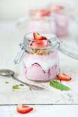 Strawberry yoghurt with honey and mint in a jar on whites chopping board