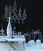 Weihnachtlich dekorierter Raum in Schwarz-Weiß mit Beistelltisch, Vase, Fellteppich, Dekokugeln & Kreidezeichnungen an Wand