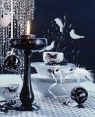 Arrangement of crockery, baubles & candlestick on black and white Christmas table