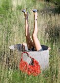 A woman's leg with high heeled sandals sticking out of a zinc tub