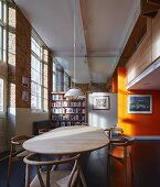 Restaurierter hoher Wohnraum mit Essbereich und Glasabtrennung über Bücherregal