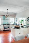 Moderne, offene, weiße Küche mit schwarzer Steinarbeitsplatte Übereck und Stuckdecke