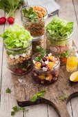 Various salads in glasses on a wooden board