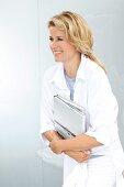 A blonde woman wearing a white shirt-blouse holding books