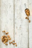 Almonds, shelled and unshelled, on a wooden surface and on a scoop