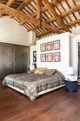 Bedroom below exposed roof structure and double bed below pictures on wall