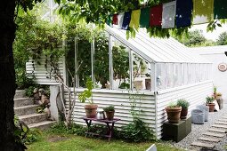 Potted plant and crates outside greenhouse with white weatherboard façade