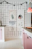 weiße Fliesenwand mit gerahmten Bildern und Lichterkette in einer Küche