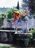 Junge Frau in transparentem Shirt und Jeans an Brunnen
