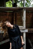 Schwarz gekleidete junge Frau vor Holzgestell