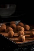 A tray of chocolate truffles being rolled in cocoa powder