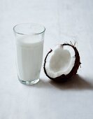 Halbe Kokosnuss und ein Glas Kokosmilch