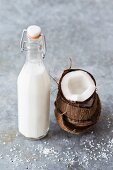 Coconut milk in a bottle with a fresh coconut