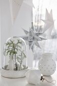 weiße Weihnachtsdeko mit Tannenzweig unter Glasglocke