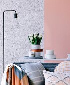 Cushions on sofa in front of console table with marble bowls and vase with white bouquet of tulips