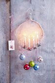 A hanger candle holder decorated with colourful Christmas baubles