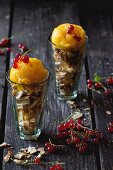 Mango sorbet with redcurrants and wafer crumbs in a glass on a wooden table