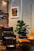 Retro armchairs at round side table and potted plant against white brick wall